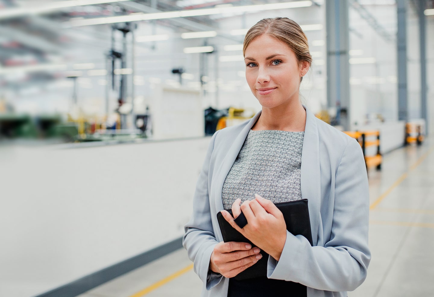 confident female business owner near factory equipment purchased with invoice financing